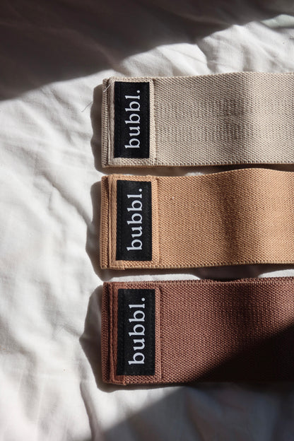 Three Bubbl. neutral beige resistance bands in light, medium and heavy resistance on white fabric