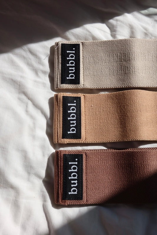Three Bubbl. neutral beige resistance bands in light, medium and heavy resistance on white fabric